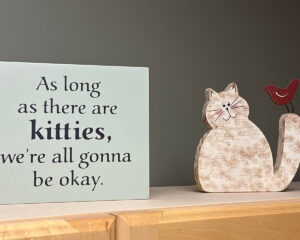 Cat sculpture and small sign with text: As long as there are kitties, we're all gonna be OK